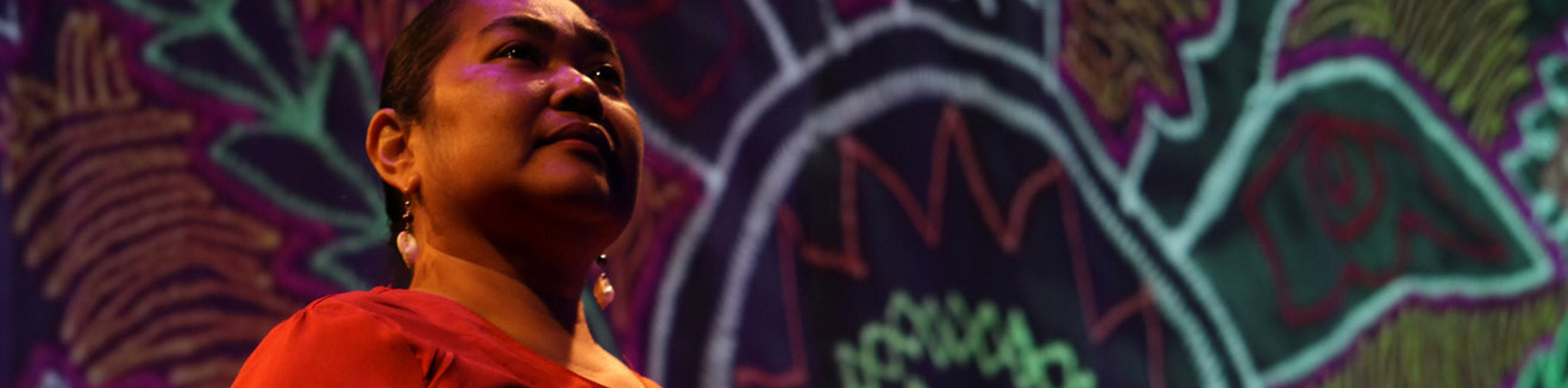 Native woman in front of banner