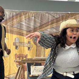 A latina woman works the crowd while a black man grimaces in a production of "Aesop's Fables."